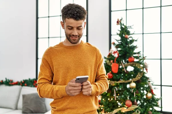 Hombre Árabe Joven Usando Teléfono Inteligente Pie Junto Árbol Navidad — Foto de Stock