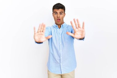 İş gömleği giyen genç İspanyol bir adam izole edilmiş arka planda duruyor. Avuçlarıyla jestleri durduruyor, kızgın ve hayal kırıklığına uğramış bir ifade sergiliyor. 