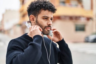 Genç Arap adam sokakta kendine güvenerek gülümsüyor.