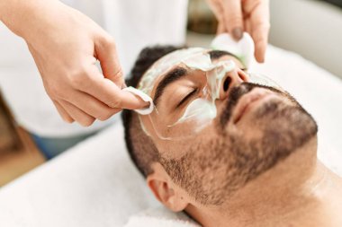 Genç İspanyol adam güzellik merkezinde yüz maskesi tedavisi görüyor.