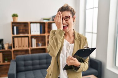 Muayenehanede çalışan genç bir kadın bir gözünü eliyle kapatıyor, yüzünde kendine güvenen bir gülümseme ve şaşırtıcı bir duygu var.. 