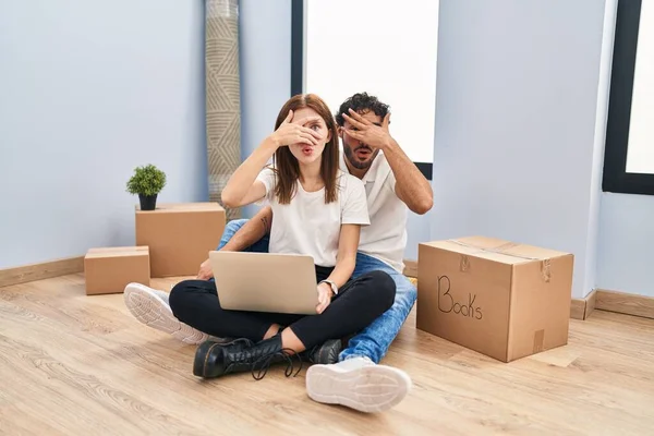 Young Couple Using Laptop New Home Peeking Shock Covering Face — Photo