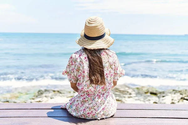 后视镜上的年轻姑娘戴着夏帽坐在海滩的长椅上 — 图库照片