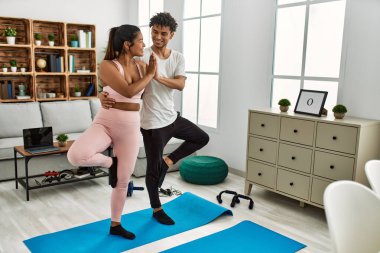 Gülümseyen genç Latin çift evde mutlu yoga pozu veriyor..