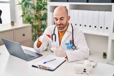 Doktor üniforması giyen genç adam klinikte analiz tüpü tutuyor.