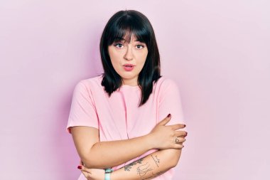 Latin kökenli genç bir kadın günlük kıyafetler giyiyor. Kış soğuğu için titriyor ve donuyor. Yüzünde üzgün ve şok ifadesi var. 