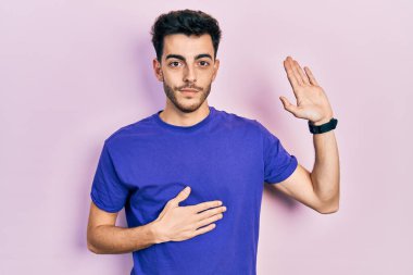 Gündelik tişörtler giyen genç İspanyol bir adam. Göğüs ve avuçlar açık yemin ediyor. Sadakat yemini ediyor. 