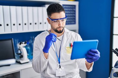 Genç Arap bilim adamı laboratuarda çalışan dokunmatik ped kullanıyor.