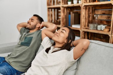 Evdeki kanepede oturan, elleri üzerinde dinlenen genç latin çift..