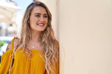 Gülümseyen genç bir kadın sokağın kenarına bakıyor kendinden emin.