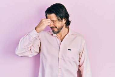 Orta yaşlı, günlük kıyafetler giyen, burnu ve gözleri ovuşturup yorgun ve başı ağrıyan beyaz bir adam. Stres ve hüsran kavramı. 