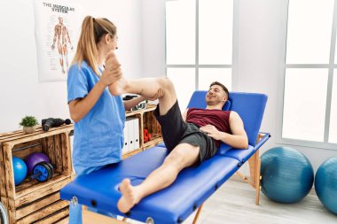 Genç İspanyol fizyoterapist kadın klinikteki adama bacak rehabilitasyonu yapıyor..