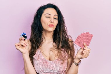 Poker oynayan genç İspanyol kadın elinde kumarhane fişleri ve kartlarla kameraya bakıyor. Öpücük atıyor ve çok seksi. aşk ifadesi. 
