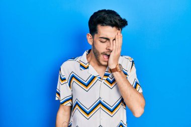 Latin asıllı genç bir adam günlük kıyafetler giyiyor. Yarı yüzünü, göz ve ağzını eliyle kapatmaktan yoruluyor. Yüzüm acıyor.. 