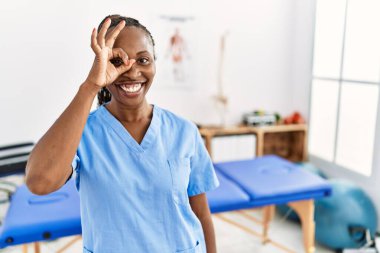 Saçları örgülü siyah bir kadın ağrı kesici kliniğinde çalışıyor. El hareketleriyle gülümsüyor, gözleriyle mutlu yüzüyle parmaklarının arasından bakıyor.. 