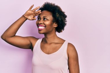 Genç Afro-Amerikalı kadın kolsuz tişört giyiyor çok mutlu ve gülümsüyor başlarını kaldırıp uzaklara bakıyor. arama kavramı. 