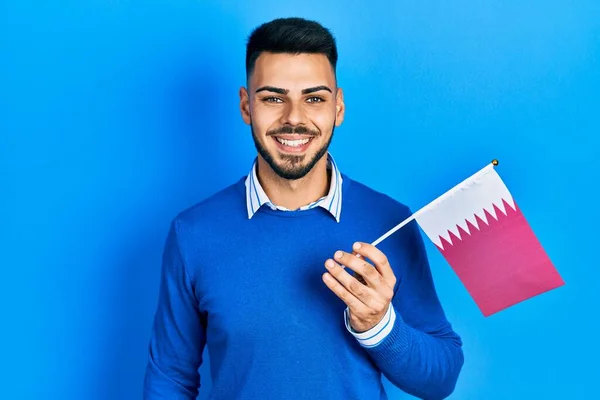 Jovem Hispânico Com Barba Segurando Bandeira Qatar Olhando Positivo Feliz — Fotografia de Stock