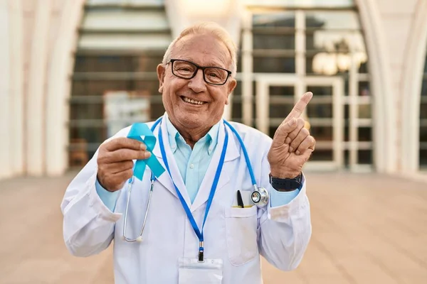 Старший Лікар Сірим Волоссям Тримає Синю Стрічку Посміхаючись Щасливим Вказуючи — стокове фото