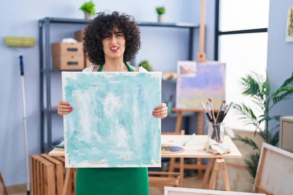 Young Brunette Woman Curly Hair Holding Painter Canvas Clueless Confused — Foto Stock