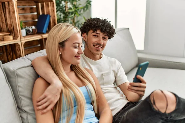 年轻夫妇用智能手机坐在家里的沙发上 — 图库照片