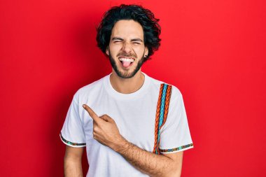 Yakışıklı İspanyol adam parmaklarını kenarı işaret ediyor. Dilini dışarı çıkarıyor. Komik bir ifadeyle mutlu.. 