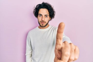 Yakışıklı, beyaz süveter giyen, elleri havada, kızgın bir ifade takınan, hiç hareket göstermeyen, yakışıklı bir İspanyol. 