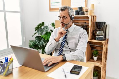 Ofiste çalışan İspanyol bir işadamı operatör kulaklığı takıyor ve sessiz olup dudaklarını öpmemi istiyor. sessizlik ve gizli konsept. 