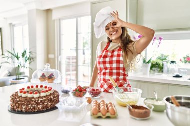 Güzel, genç, esmer pasta şefi kadın mutfakta hamur işi pişiriyor. El hareketleriyle gülümsüyor, gözleriyle gülen parmaklarıyla bakıyor.. 