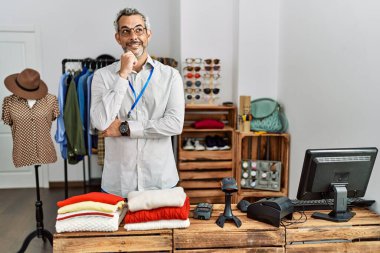 Orta yaşlı İspanyol bir adam perakende mağazasında yönetici olarak çalışıyor. Elleri çenesinde soru sormayı düşünüyor. Düşünceli bir ifade. Gülümseyen ve düşünceli bir yüz. şüphe kavramı. 