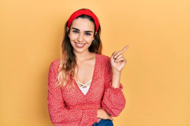 Gündelik kıyafetler giyen genç İspanyol kız gülümseyerek mutlu bir şekilde elini ve parmağını kenarda gezdiriyor. 