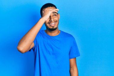 Genç, Afro-Amerikan bir adam günlük mavi tişört giyiyor çok mutlu ve gülümsüyor başlarını kaldırarak uzaklara bakıyor. arama kavramı. 