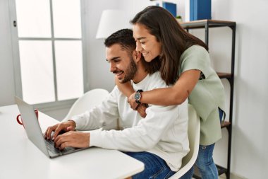 Laptop kullanan ve evde kahve içen genç bir çift..