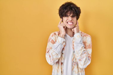 Gündelik tişört giyen genç adam yüksek sesli müzik sesi için kulaklarını parmaklarıyla kapatıyor. sağır kavramı. 