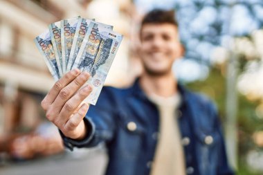 Genç İspanyol gülümseyen adam, şehirde Peru sol banknotlarını tutarken mutlu.