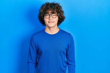 Yüzünde mutlu ve havalı bir gülümseme olan günlük kıyafetler ve gözlük takan yakışıklı bir genç. şanslı kişi. 