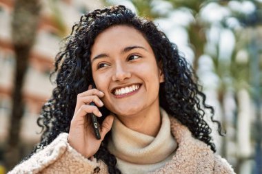 Genç İspanyol kadın gülümsüyor. Kendine güveniyor. Akıllı telefondan konuşuyor.