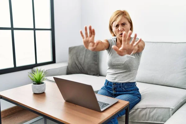 Middle Age Blonde Woman Using Laptop Home Doing Stop Gesture — Stockfoto