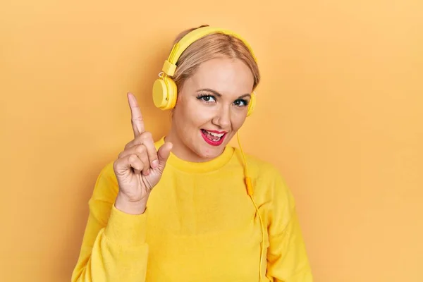 Mujer Rubia Joven Escuchando Música Usando Auriculares Mostrando Apuntando Hacia —  Fotos de Stock