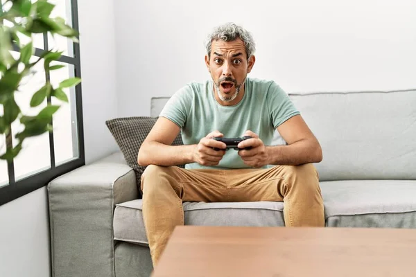 Homem Hispânico Meia Idade Jogando Videogame Sentado Sofá Assustado Surpreso — Fotografia de Stock