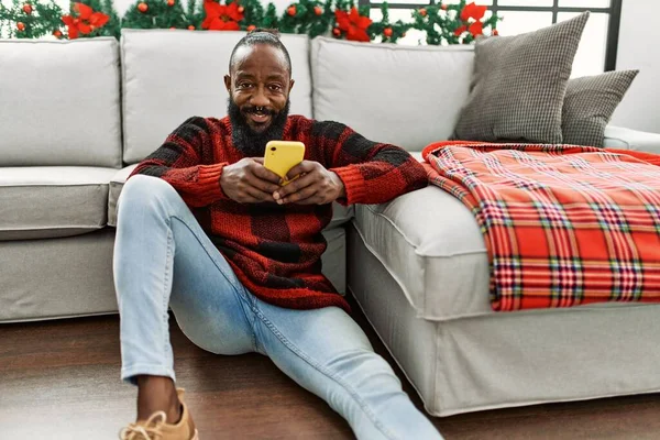 Mladý Africký Američan Pomocí Smartphone Sedí Vánočního Dekoru Doma — Stock fotografie