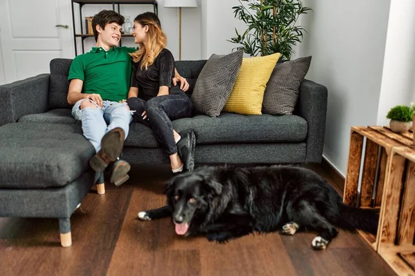 Joven Pareja Caucásica Sonriendo Feliz Abrazándose Sentado Sofá Con Perro —  Fotos de Stock