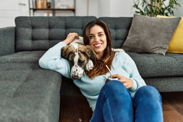 Young woman hugging dog drinking mate infusion at home