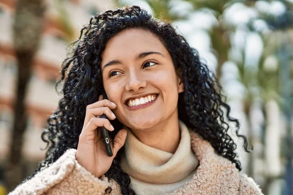 Genç İspanyol kadın gülümsüyor. Kendine güveniyor. Akıllı telefondan konuşuyor.