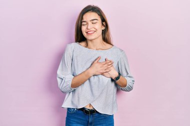 Sıradan kıyafetler giyen, göğsünde elleri kapalı, yüzünde minnet dolu bir jest olan beyaz bir genç kız. sağlık kavramı. 