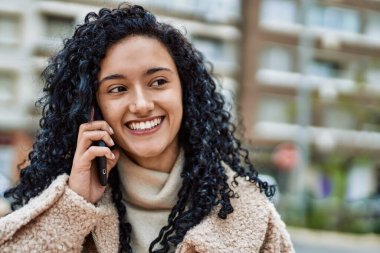 Genç İspanyol kadın gülümsüyor. Kendine güveniyor. Akıllı telefondan konuşuyor.