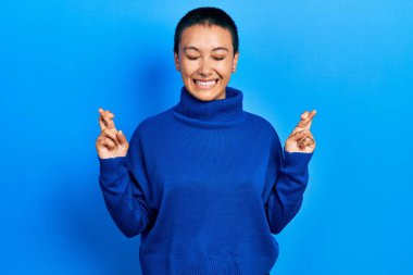 Kısa saçlı, balıkçı yaka kazak giyen güzel İspanyol kadın umut ve gözleri kapalı bir şekilde gülümseyerek işaret ediyor. Şans ve batıl inançlar. 