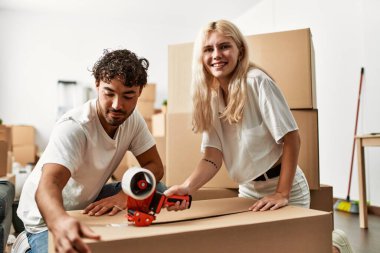 Genç ve güzel bir çift gülümsüyor. Yeni evlerinde karton kutular paketliyorlar..