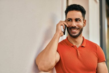 Genç İspanyol adam gülümsüyor. Şehirdeki akıllı telefondan konuşuyor..