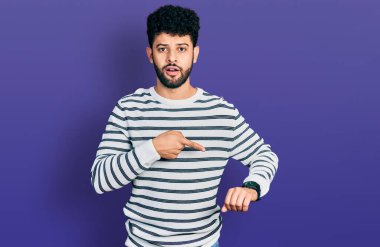 Sakallı, sıradan çizgili süveter giyen genç bir Arap saati izlemek için acele ediyor, sabırsız, geç kaldığı için kızgın ve sinirli. 