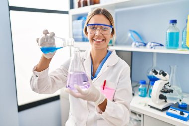 Laboratuvarda test tüpüne sıvı döken genç İspanyol bilim kadını.